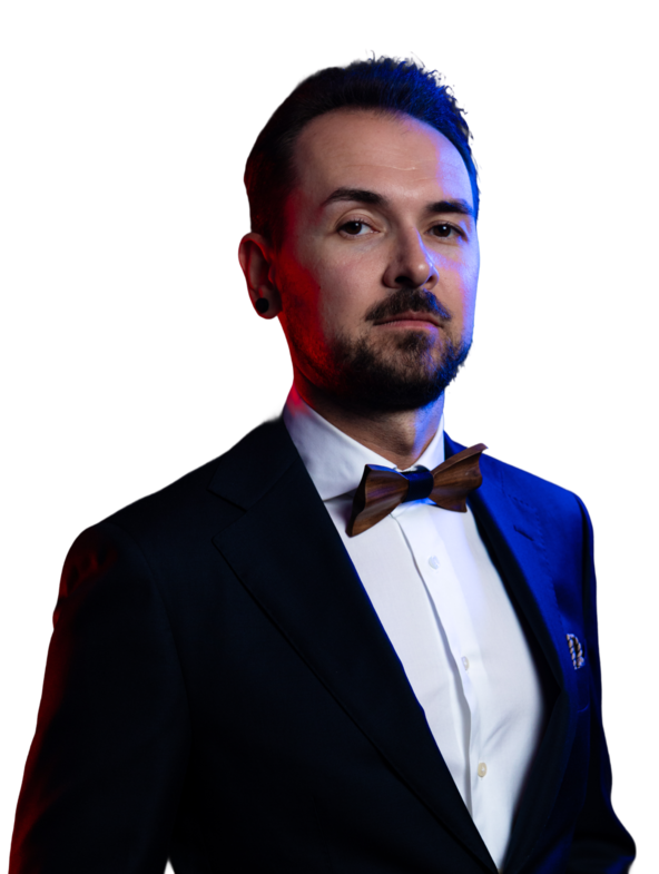 Alexej in Anzug mit Fliege, schaut ernst in die Kamera, Hintergrund in dunklen Farben.